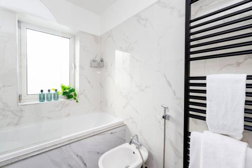a white bathroom with a tub and a sink at Excellent 3 bed House Hyde Park in London