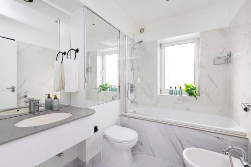 a white bathroom with a tub and a toilet and a sink at Excellent 3 bed House Hyde Park in London