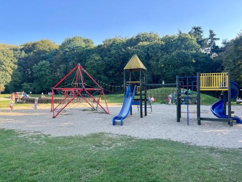 a playground with slides and play equipment in a park at Stylish downtown loft and opposite park in Maldegem