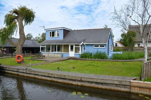 a blue house on the side of a river at Bittern - Horning holiday home in Horning