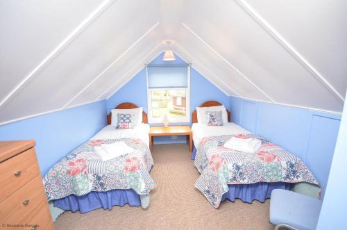 a attic room with two beds and a window at Bittern - Horning holiday home in Horning
