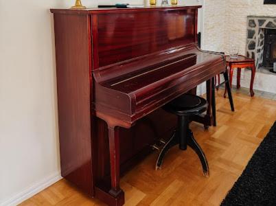 a brown piano in a room with a stool at Paradise-Silvergruvan in Hällefors