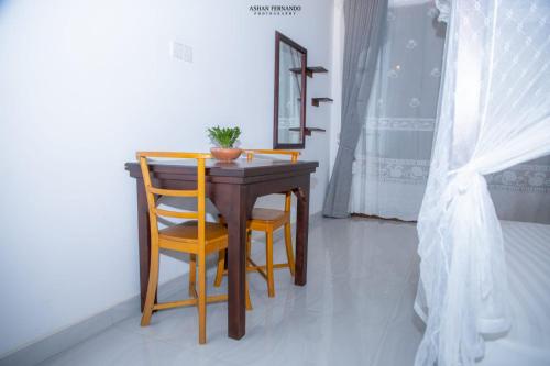 a wooden table with two chairs and a plant on it at Isamar beach front in Marawila