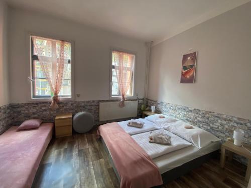 a bedroom with two beds and two windows at Penzion Jáchymov Pod Lanovkou in Jáchymov