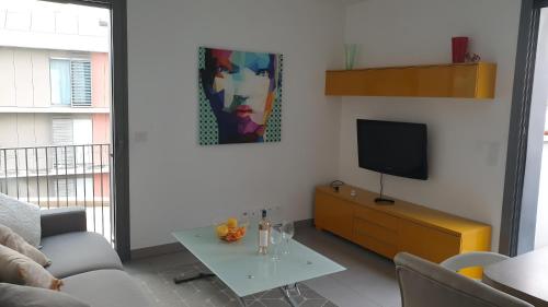 un salon avec une télévision et une table dans l'établissement Modern Top-Floor Apartment with Terrace, Pool & Free Private Parking, à Roquebrune-Cap-Martin