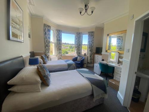 トーキーにあるBuckingham Lodge Guest Houseのベッド2台と机があるホテルの部屋