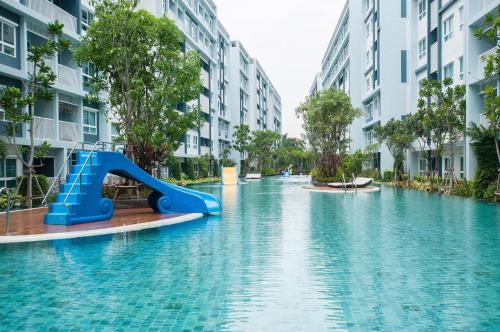 a water slide in the middle of a pool with buildings at The Trust Hua Hin kitty room in Hua Hin