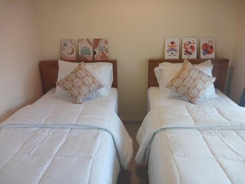 2 bedden in een kamer met witte lakens en kussens bij Bali Oma Living in Denpasar