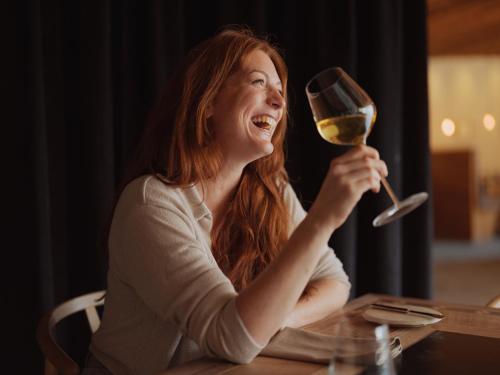 a woman sitting at a table with a glass of wine at Fuxbau in Stuben am Arlberg