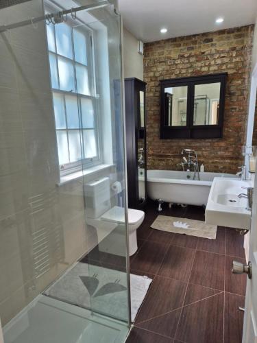 a bathroom with a shower and a toilet and a sink at Coach House Greenwich in London