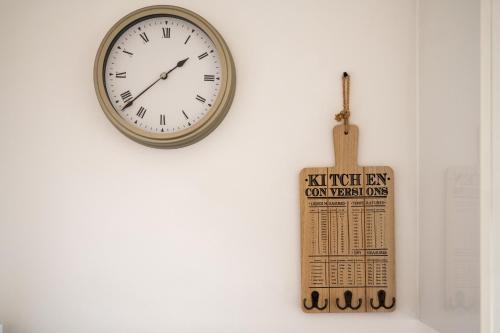 a clock on a wall next to a wooden thermometer at Hinckley Flats in Hinckley