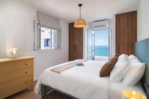 a bedroom with a bed with a view of the ocean at Villa Omega - Coastal Calm at Moonlight Villas in Pachyammos