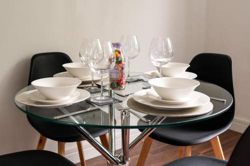 a glass table with plates and wine glasses on it at Hinckley Flats in Hinckley