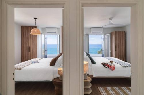 two beds in a room with a view of the ocean at Villa Akroyiali - Seafront Serenity with Shared Pool in Pachyammos