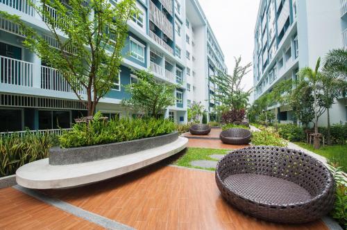 a courtyard with two benches and trees and buildings at The Trust Hua Hin kitty room in Hua Hin