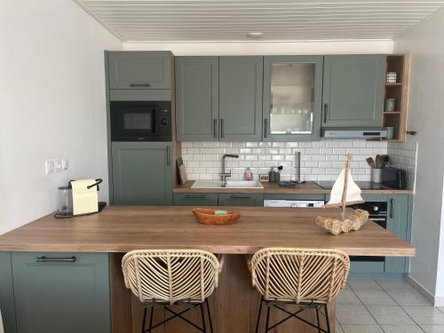 une cuisine avec des armoires bleues et un comptoir avec deux chaises dans l'établissement Charmante Maison de Plage, à Bretignolles-sur-Mer