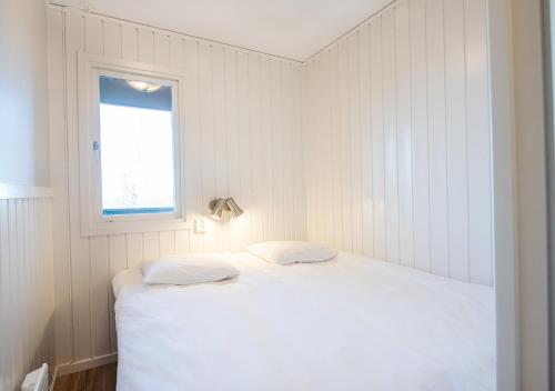 a white bedroom with a bed and a window at Stöten Mitt Lägenheter in Sälen