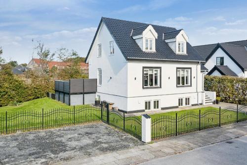 a white house with a black roof and a fence at Lejlighed med egen indgang in Hjørring