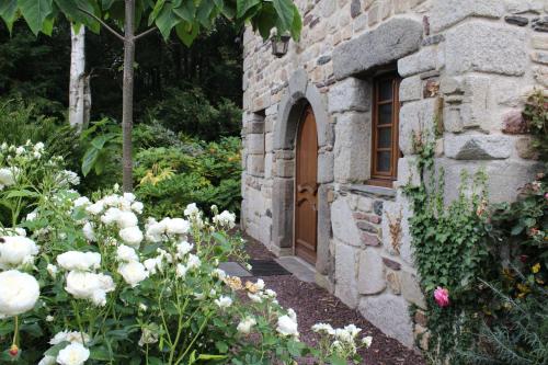 - un bâtiment en pierre avec une porte et quelques fleurs dans l'établissement Gîte de l'Ermitage en Brocéliande 2 à 4 personnes, à Mauron