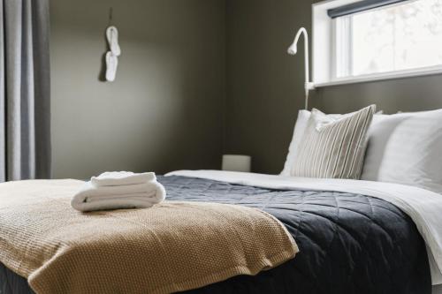 a bed with two towels sitting on top of it at Guestly Homes - Stylish 3BR Stay in Peaceful Surroundings in Piteå