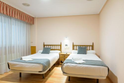 a bedroom with two beds and a window at Hotel Alda Xinzo in Xinzo de Limia