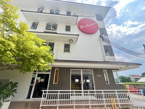a building with a large pink sign on it at Ruan Plaisoi Apartment in Bangkok