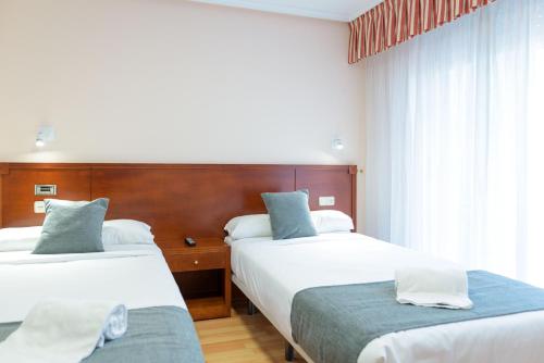 a hotel room with two beds and a window at Hotel Alda Xinzo in Xinzo de Limia