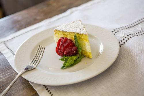 a piece of cake with strawberries on a plate with a fork at Locanda Monte Baldo in Malcesine