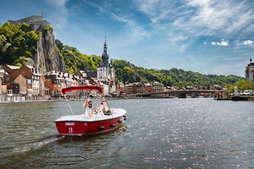 two people on a boat in the water near a city at Pénichettes Dinant Evasion in Dinant