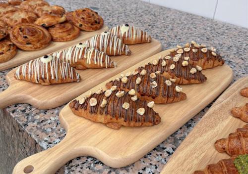 three wooden cutting boards with breads and pastries on them at Vender Hotel in Taif