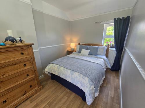 ein Schlafzimmer mit einem Bett, einer Kommode und einem Fenster in der Unterkunft Newly Renovated Country Cottage in Portadown