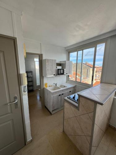 une cuisine avec un comptoir et une grande fenêtre dans l'établissement Appartement lumineux au coeur de Valence 52, à Valence