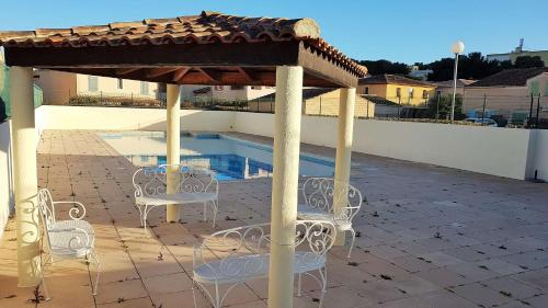 une terrasse avec des chaises, un kiosque et une piscine dans l'établissement T2 duplex dans résidence sécurisée, parking privé, piscine, climatisation, internet, à La Seyne-sur-Mer