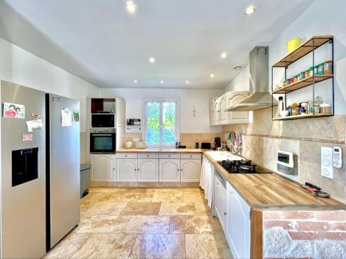 Il comprend une grande cuisine avec des placards blancs et un réfrigérateur. dans l'établissement La Maison des Copains à Moussac, à Moussac