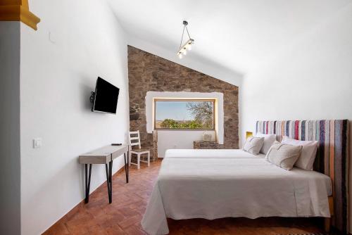 a bedroom with a bed and a desk and a window at Casas do Monte I - T2 in Mértola