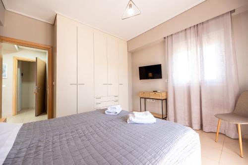 a bedroom with a bed and a chair and a television at DreamCoast Apartments I in Artemida