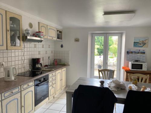 une cuisine avec des armoires blanches et une table avec des chaises dans l'établissement Location, à La Celle-sous-Gouzon