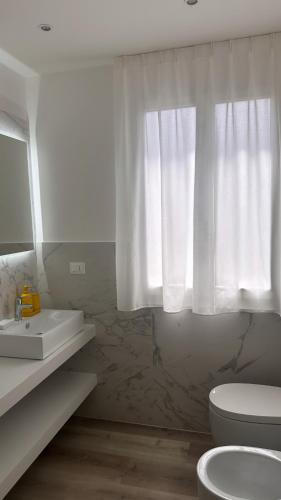 a bathroom with a sink and a toilet and a window at SUITE Rosso Conero - Le Grotte Rooms And Apartments in Camerano