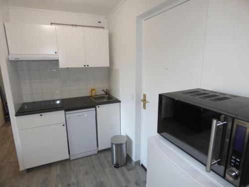 La cuisine est équipée de placards blancs et d'un four micro-ondes noir. dans l'établissement Piscine, plages à proximité, internet et parking privé, à La Seyne-sur-Mer