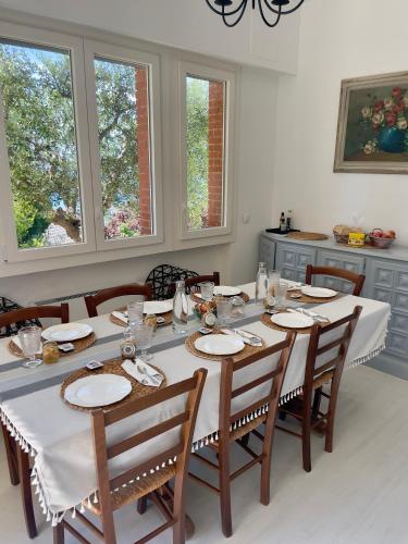 a dining room with a table with chairs and windows at Villa Gaia - Luxury Villa, pool & wellness rooms in Bordighera