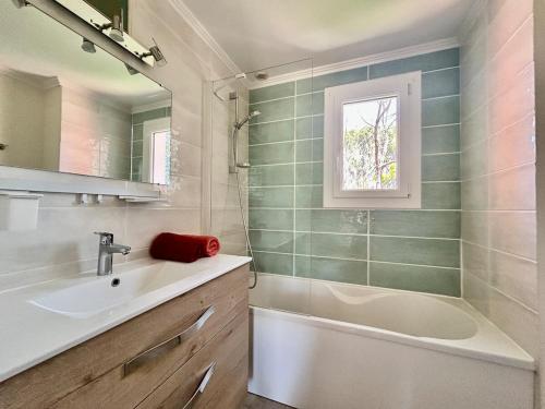 La salle de bains est pourvue d'un lavabo, d'une baignoire et d'une fenêtre. dans l'établissement Les Restanques Maison 3 Pins, à Grimaud