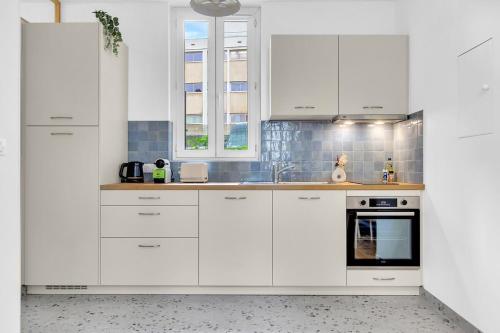 - une cuisine blanche avec des placards blancs et une cuisinière dans l'établissement L'Art & Lettres - F2 pour 2 personnes - Fac de Lettre - Arrêt de Bus, à Nancy