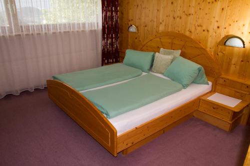 1 dormitorio con cama de madera y almohadas verdes en Apart Adele en Arzl im Pitztal