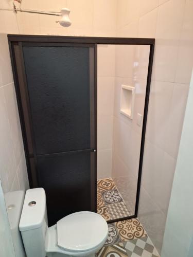 a bathroom with a toilet and a glass door at Kitnet Completa perto da Praia e do Centro, Roupas de Cama e Banho in Ilha Comprida