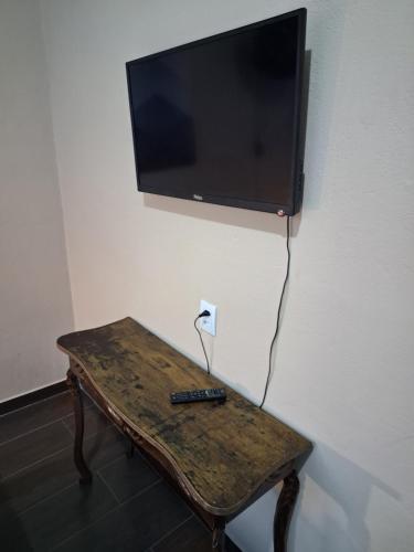 a tv on a wall with a remote control on a table at Kitnet Completa perto da Praia e do Centro, Roupas de Cama e Banho in Ilha Comprida