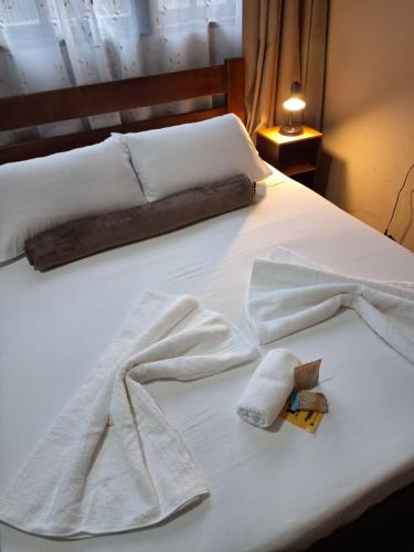 a bed with two towels on it with at Kitnet Completa perto da Praia e do Centro, Roupas de Cama e Banho in Ilha Comprida