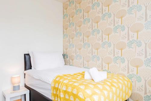 a bedroom with a bed and a wall with trees wallpaper at Spacious 4 Bedroom Home in Central Milton Keynes in Milton Keynes