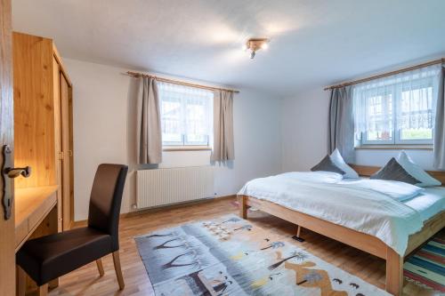 a bedroom with a bed and a desk and a chair at DORF 77 Apartment in Elbigenalp
