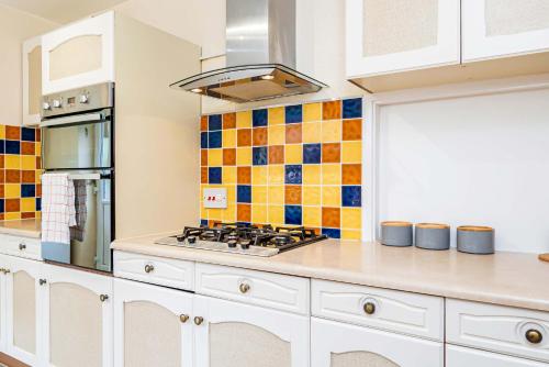 a kitchen with white cabinets and a stove top oven at Spacious 4 Bedroom Home in Central Milton Keynes in Milton Keynes