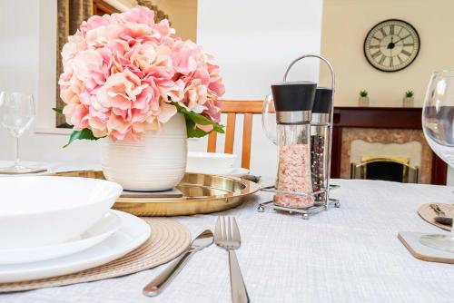 a table with a vase with pink flowers on it at Spacious 4 Bedroom Home in Central Milton Keynes in Milton Keynes